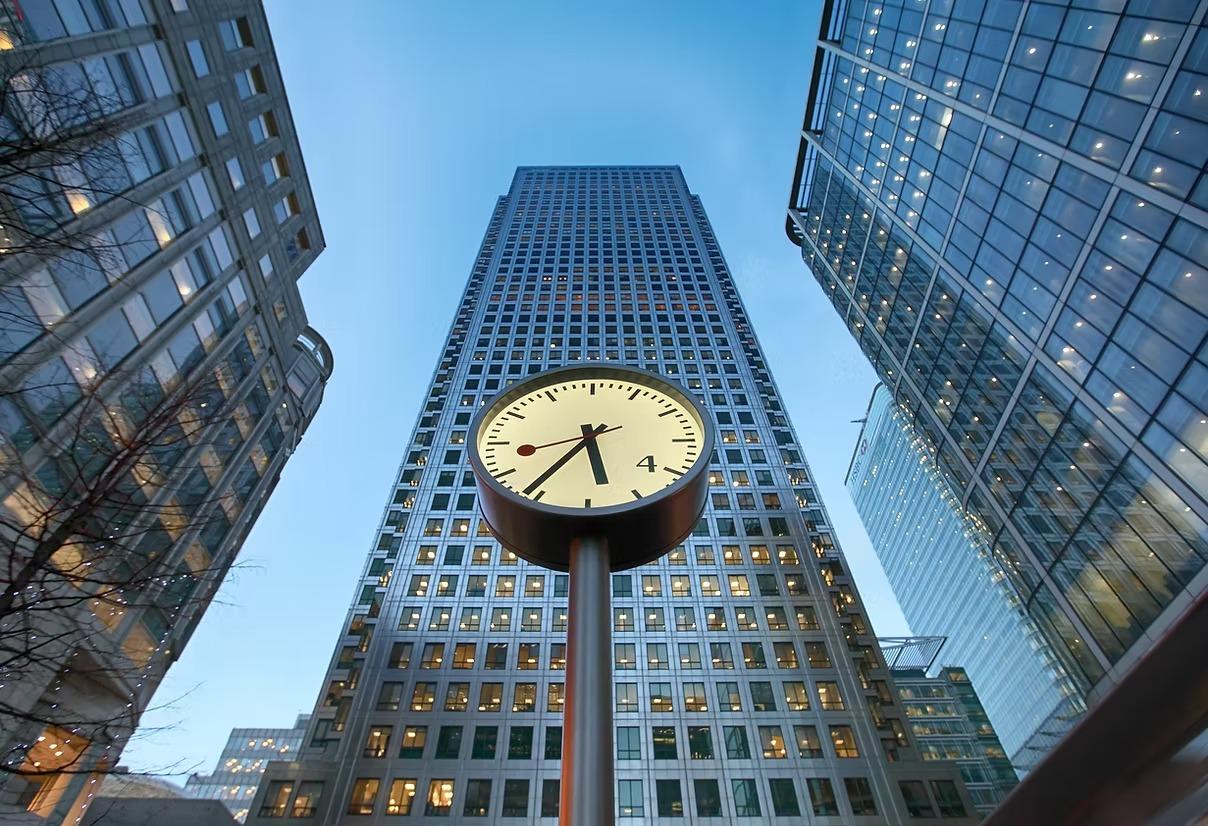 Clock tower at Canary Wharf financial district in London with One Canada Square skyscraper in the background